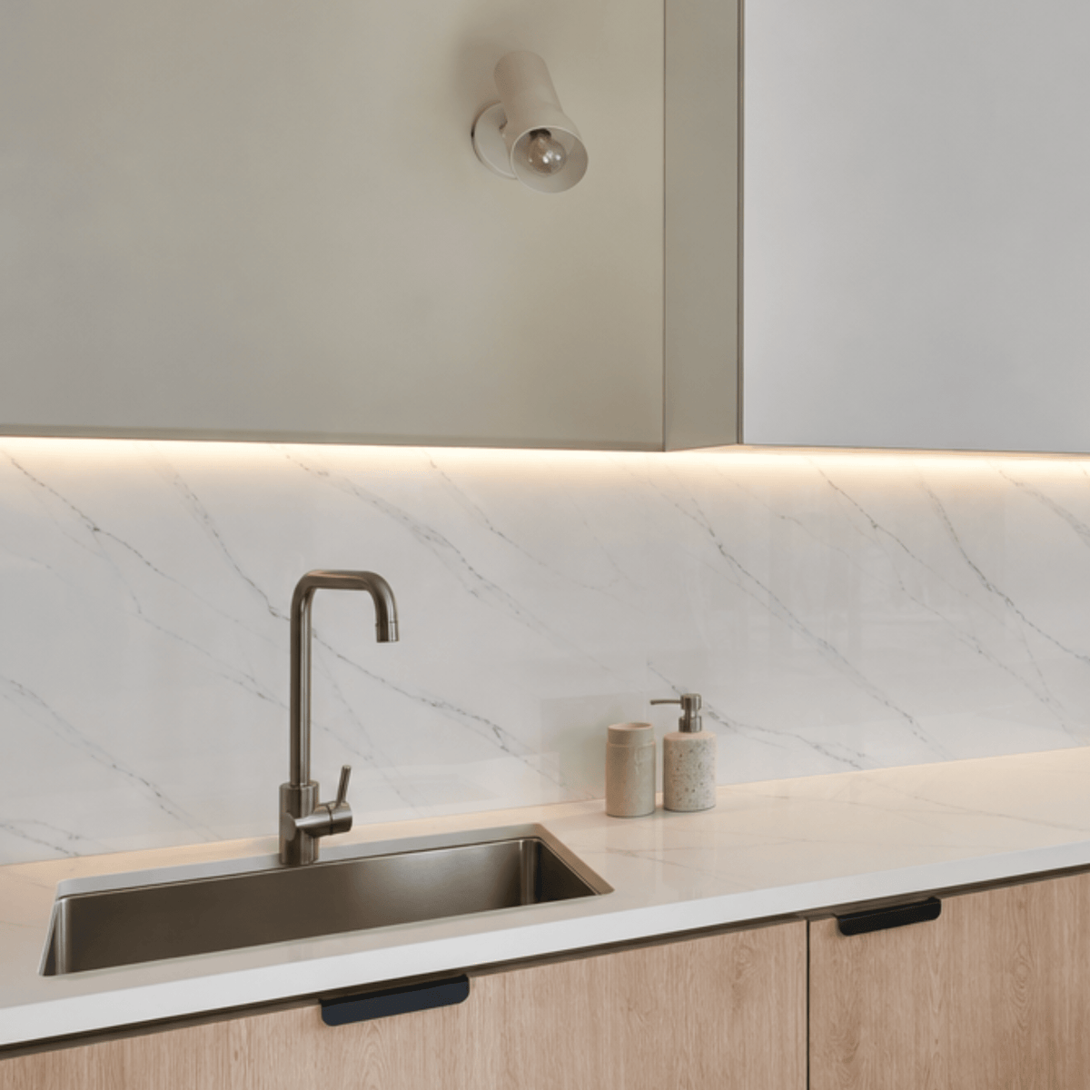 Placa PVC símil mármol blanco Carrara en la pared de una cocina, detrás de la mesada y la pileta