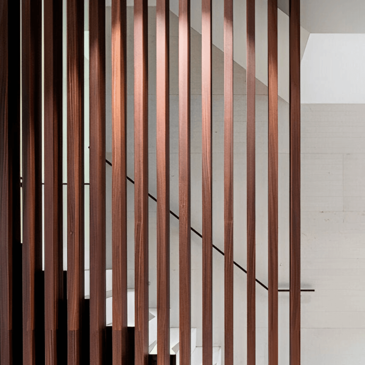 Vigas WPC verticales color nogal oscuro como separador junto a una escalera