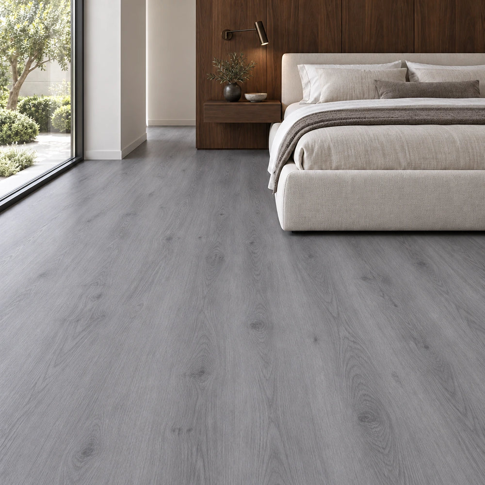 Dormitorio moderno con piso vinílico SPC símil roble gris, cama tapizada en lino y gran ventanal al jardín.
