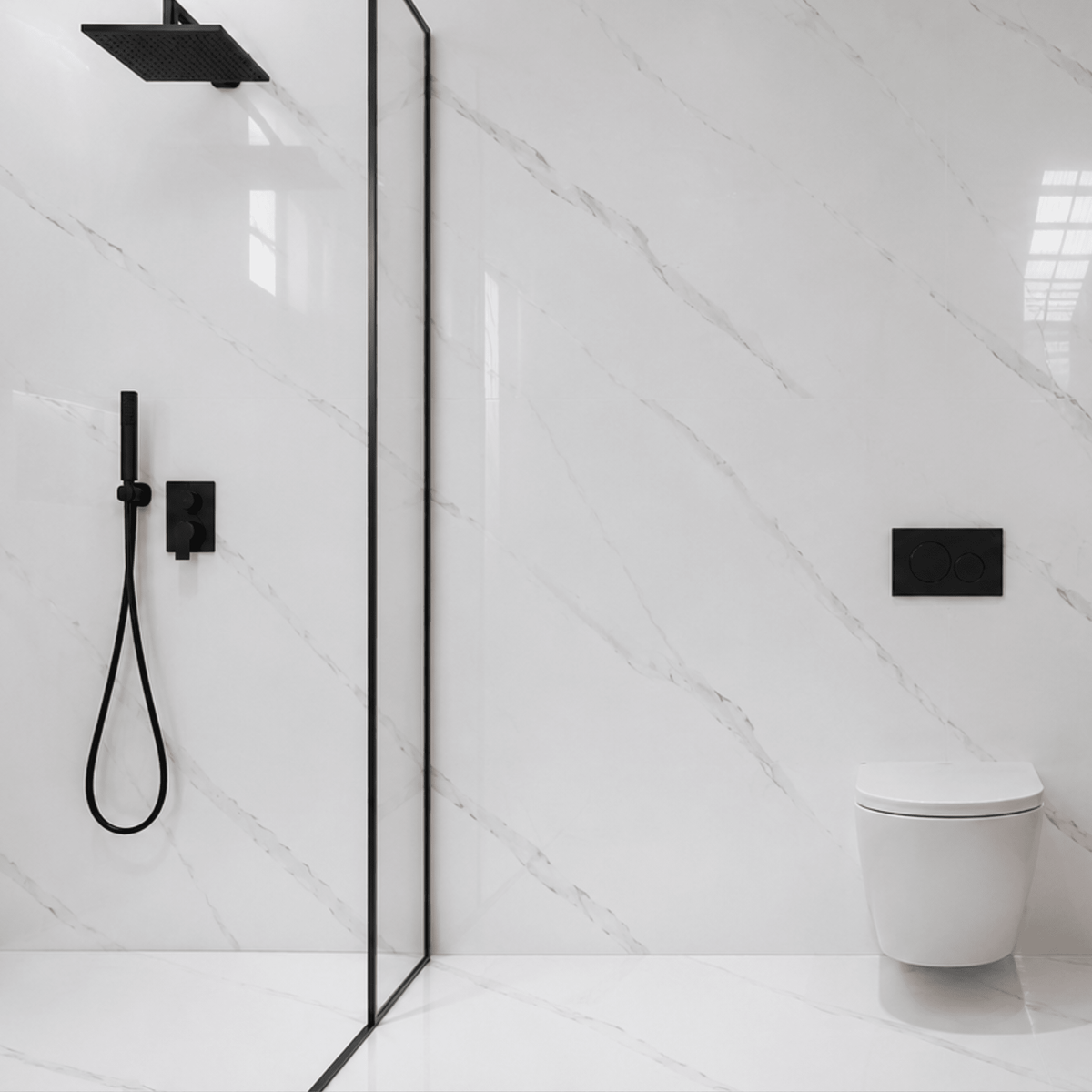 Placa PVC símil mármol blanco Carrara en la pared de un baño, con ducha de mampara y grifería negra