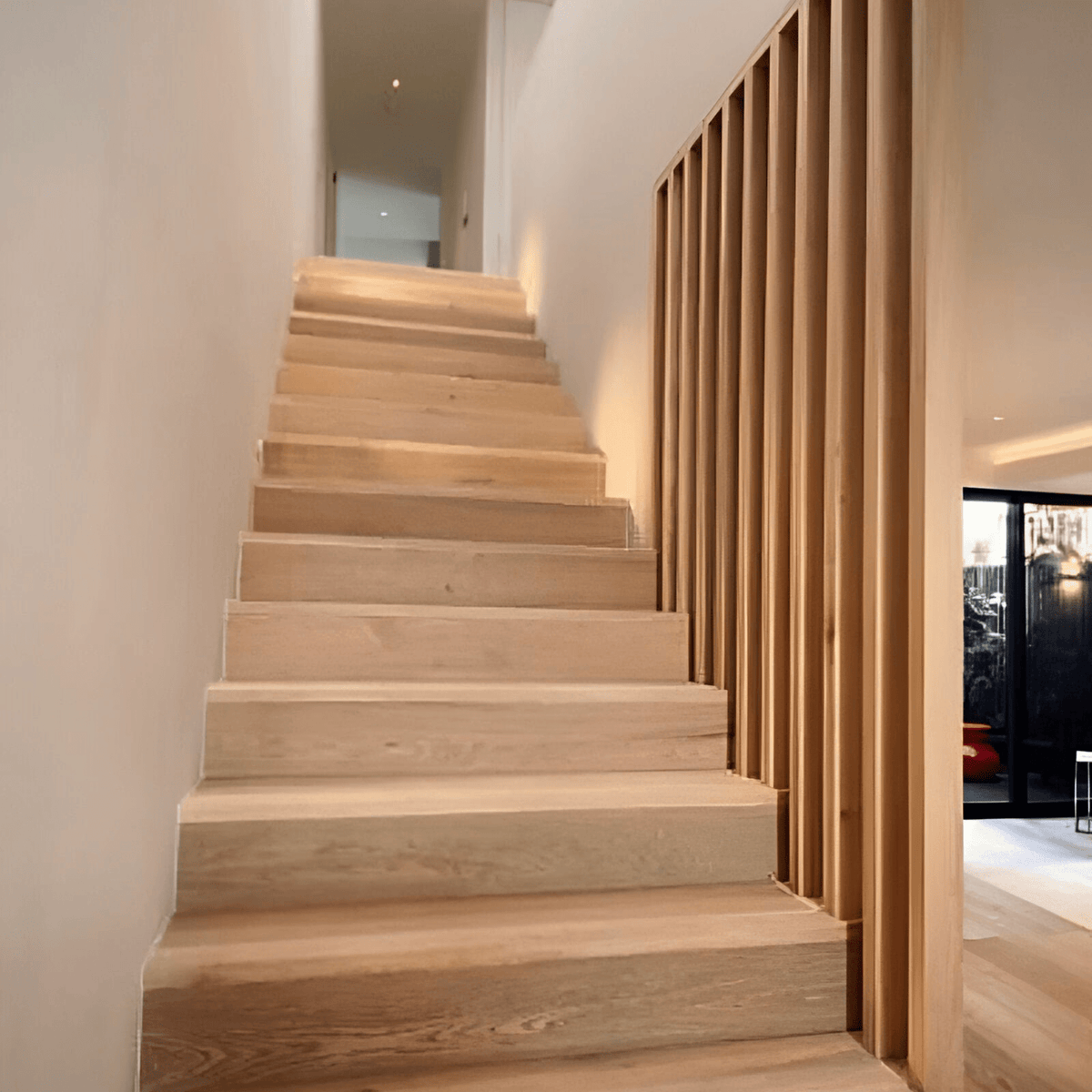 Escalera con vigas WPC verticales color madera clara como baranda