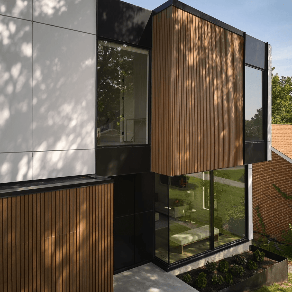 Fachada de casa moderna con revestimiento de panel WPC color teca en listones verticales