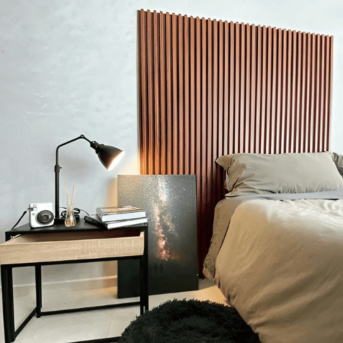 Pared de dormitorio con panel WPC de listones color madera rojiza detrás de la cama